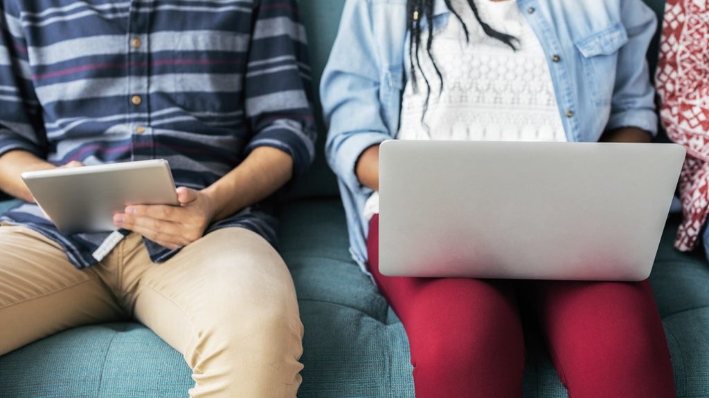 Zwei Mitarbeitende prüfen digitale Informationen gemeinsam auf Laptop und Tablet